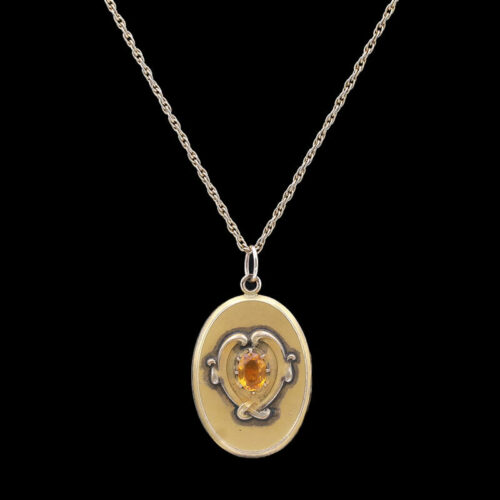 a gold necklace with an orange stone in the center