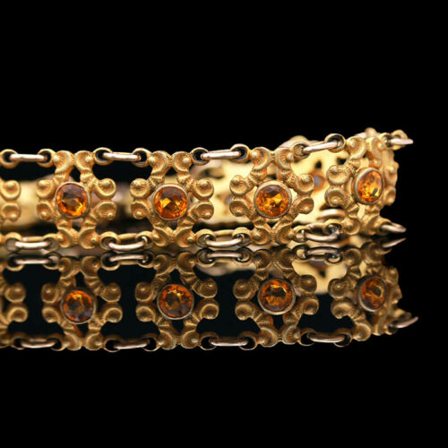 a close up of a gold bracelet with orange stones