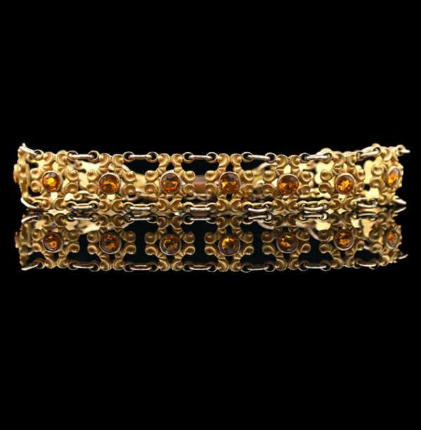 a gold bracelet with orange stones on it