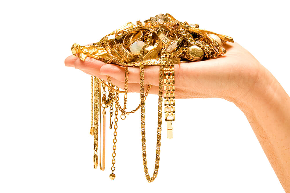 a hand holding a gold necklace with chains