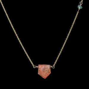 a gold chain with a red stone on it