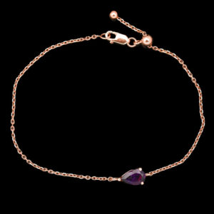 a gold bracelet with a purple stone on it