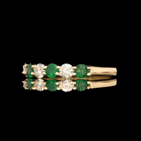 three emerald and diamond rings on a black background