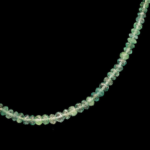 a necklace with green glass beads on a black background