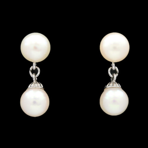 pair of earrings with white pearls on black background
