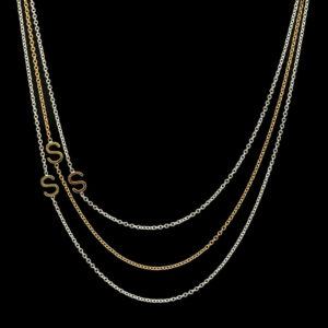 a gold necklace with three chains and two letters