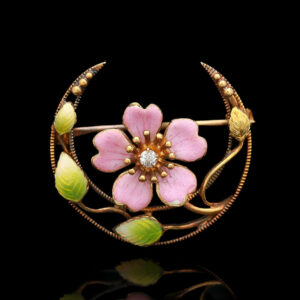a pink flower brooch sitting on top of a black surface