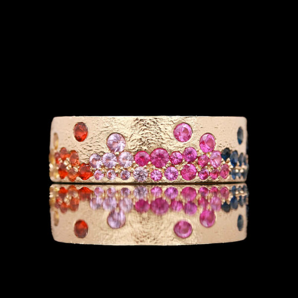a gold ring with pink, red and blue stones