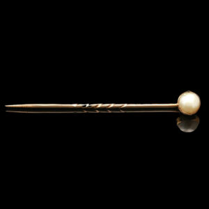 a gold and pearl brooch on a black background