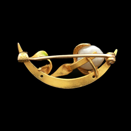 a gold brooch with an arrow and two pearls