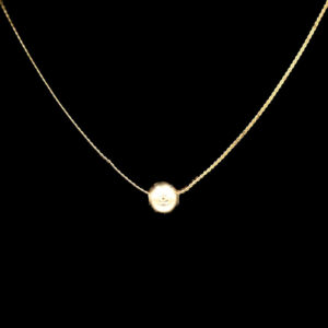 a gold necklace with a white pearl on it