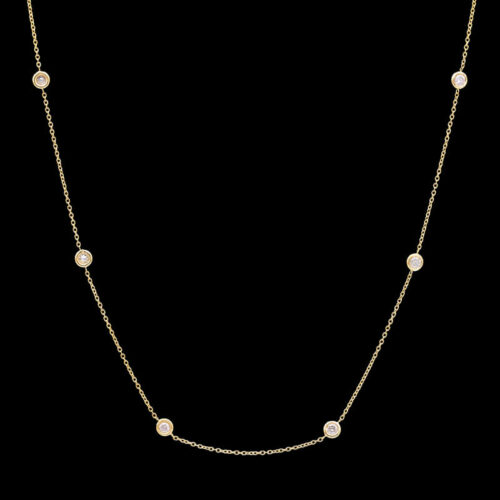 a gold necklace with pearls on a black background