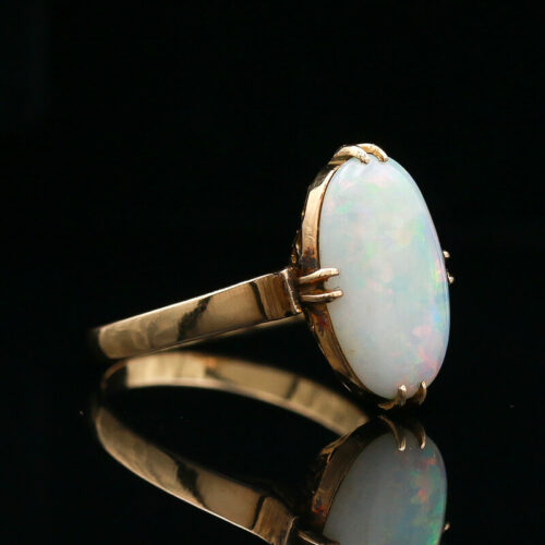 an opalite and diamond ring on a black surface