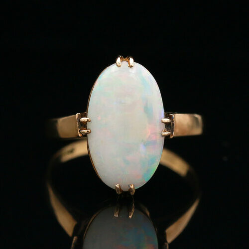 a white opal ring sitting on top of a black surface