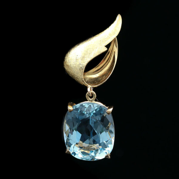 a gold pendant with an aqua blue stone