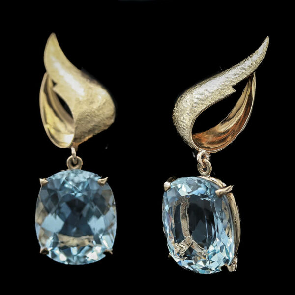 a pair of earrings with blue topaz and gold accents