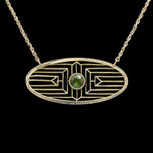 a gold necklace with a green stone in the center