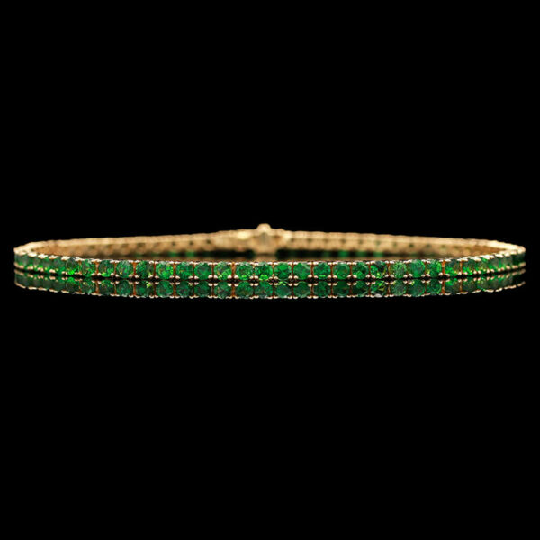 a green and gold bracelet on a black background