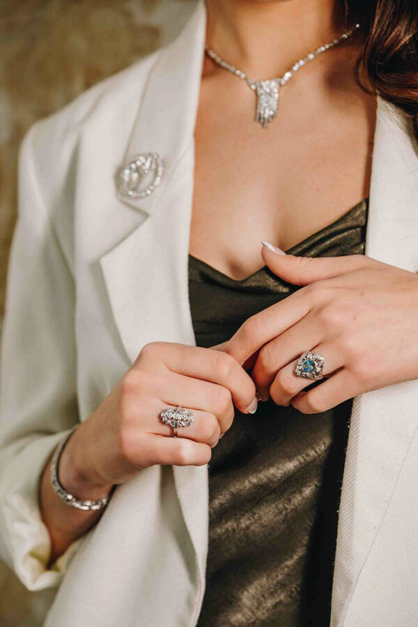 a woman wearing a white jacket and diamond ring
