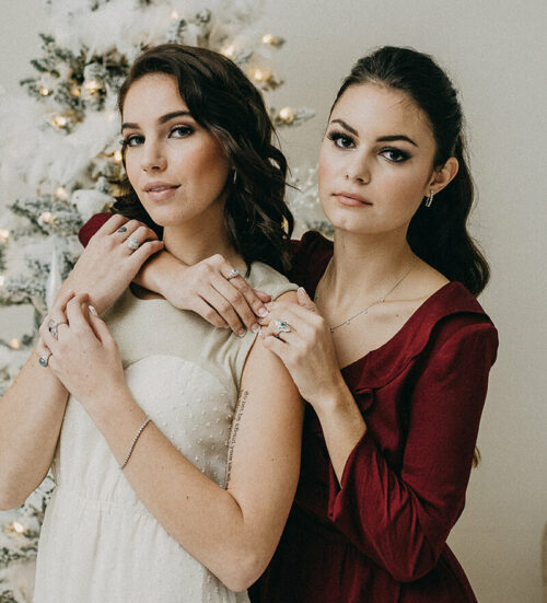 two women standing next to each other near a christmas tree