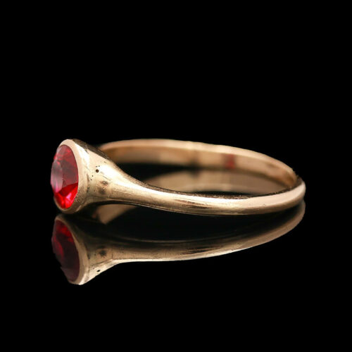 a gold ring with a red stone on it