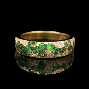 a gold ring with green stones and diamonds