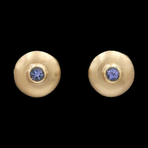 a pair of gold earrings with a blue stone