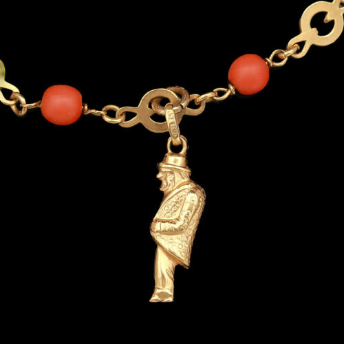 a gold chain with a red bead and an egyptian charm