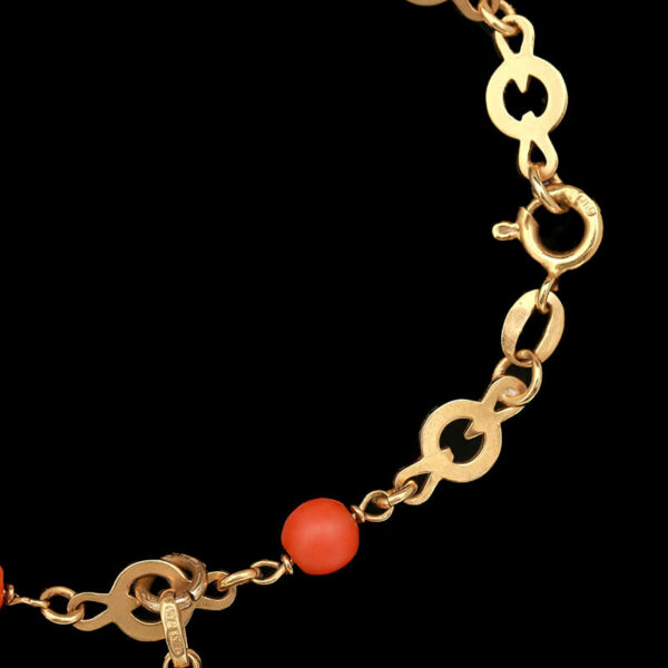a gold bracelet with red beads and a cross