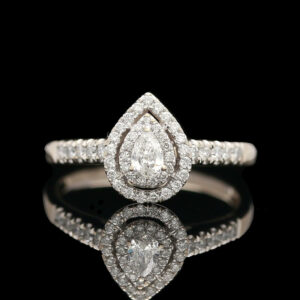 a pear shaped diamond engagement ring on a reflective surface