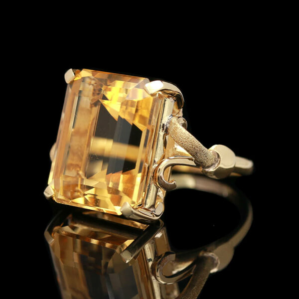 a fancy yellow diamond ring on a reflective surface