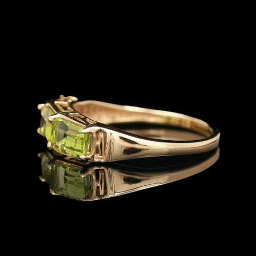 a yellow gold ring with two green stones