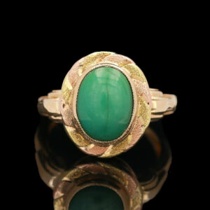 a gold ring with a green stone in the center