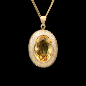 a pendant with a large yellow stone in it