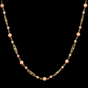 a gold necklace with pink beads on a black background