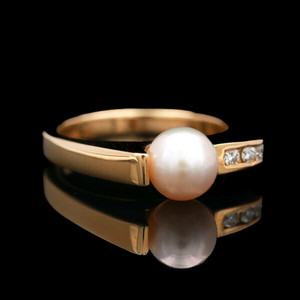 a pearl and diamond ring on a black background