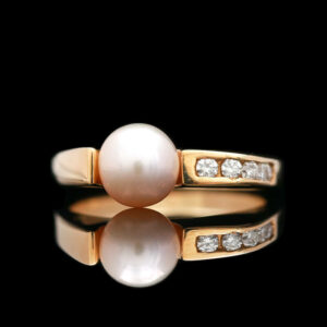 a pearl and diamond ring on a black background