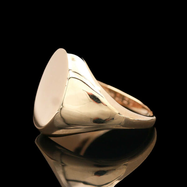 a gold signet ring on a reflective surface