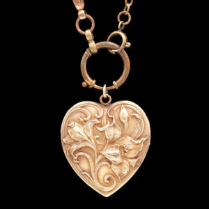 a gold heart shaped pendant on a black background