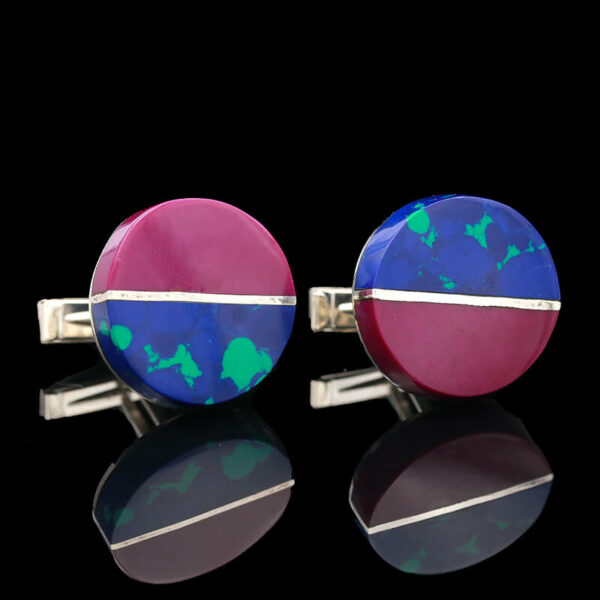 two cufflinks with blue and pink designs on them