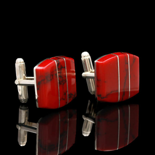 a pair of red and silver cufflinks on a black background