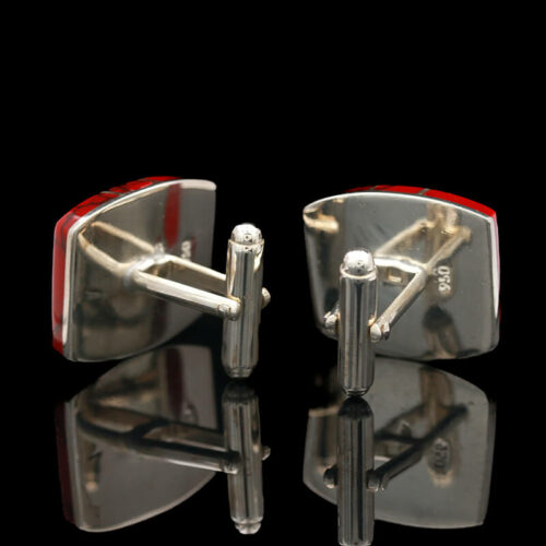 pair of silver cufflinks with red stripe on black background