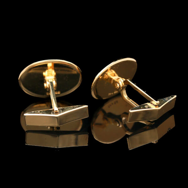 a pair of gold toned cufflinks on a black background