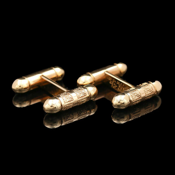 two gold cufflinks with writing on them