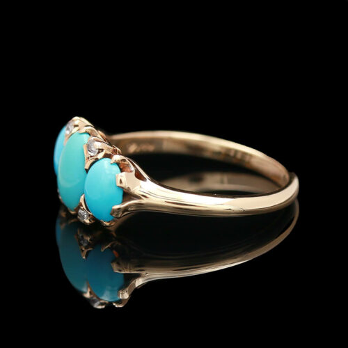 a gold ring with two turquoise stones on it