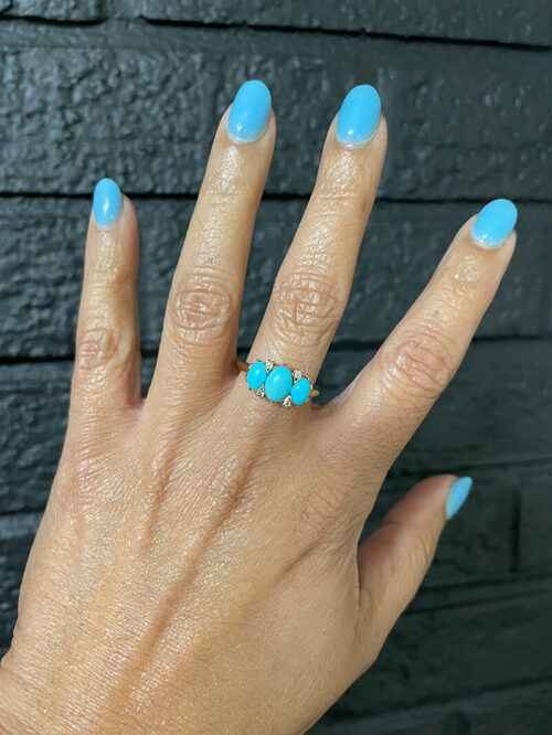 a woman's hand with blue nails and a turquoise ring