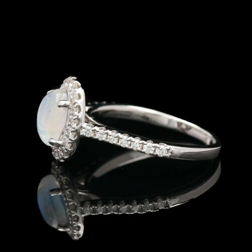a white gold ring with an oval stone surrounded by diamonds