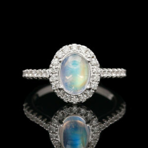 a ring with an oval shaped rainbow stone surrounded by diamonds
