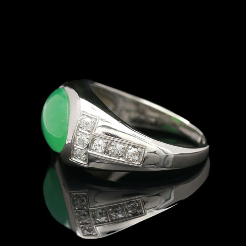 a green jade and diamond ring on a reflective surface