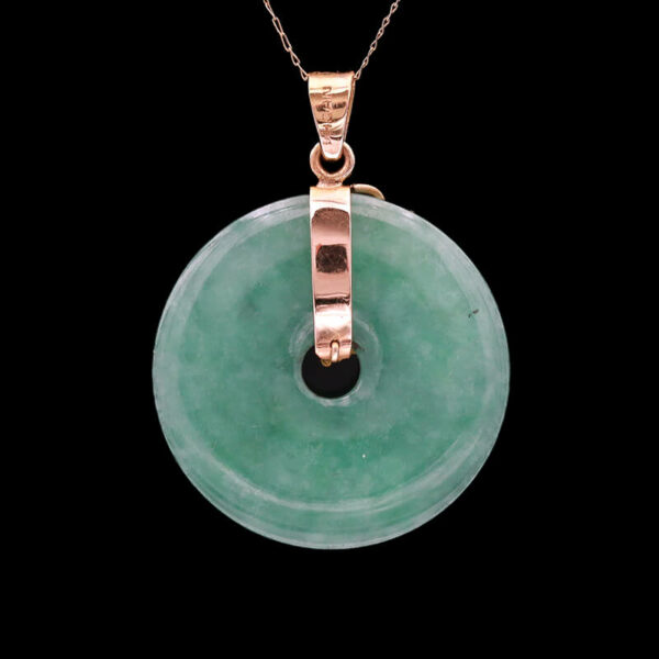 a pendant with a green stone in the middle